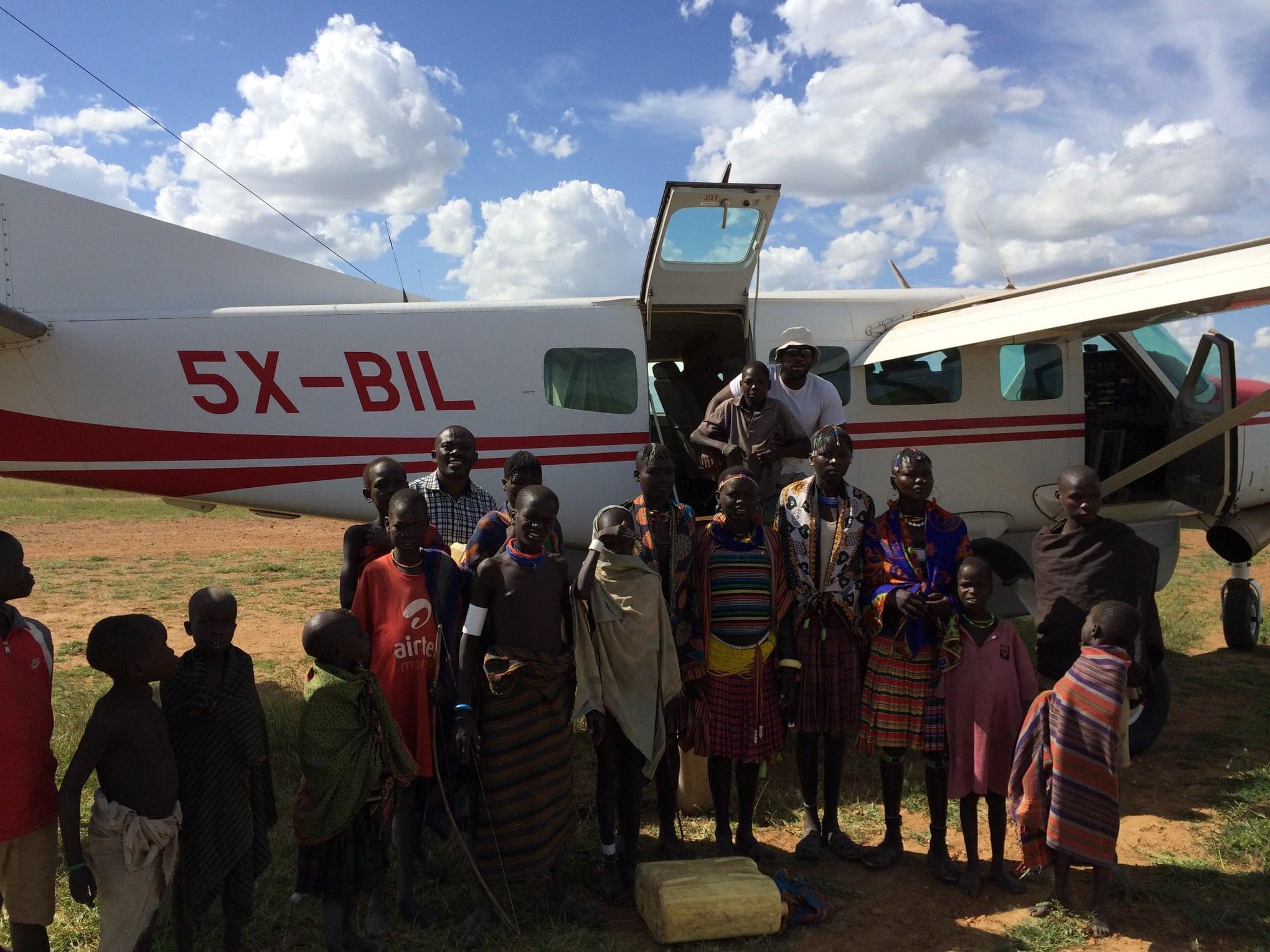Charis Bible College graduate flys into a remote African village and poses with large group of people.